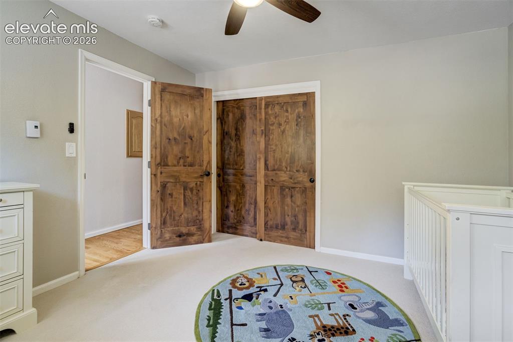 Image 27 of 50: Main level bedroom featuring a ceiling fan with integrated lighting, a wall