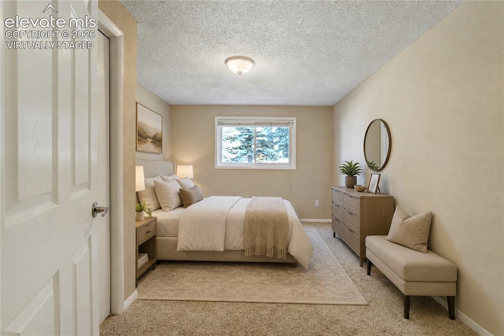 Image 32 of 50: Spacious main level bedroom featuring light-toned walls, a large window wit