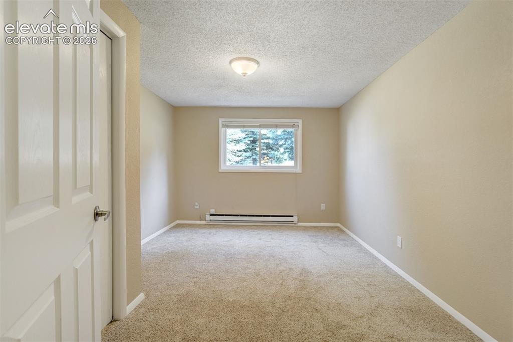 Image 33 of 50: Virtually Staged Basement bedroom featuring a window with exterior tree vie