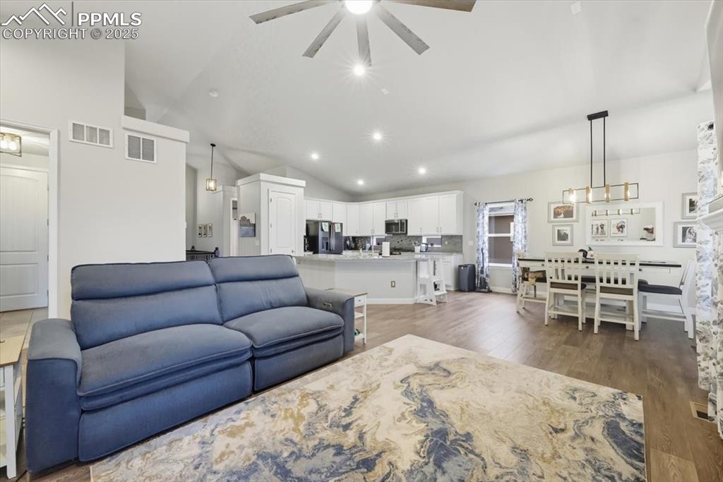 Image 10 of 47: Living room featuring vaulted ceiling, dark wood-style floors, recessed lig