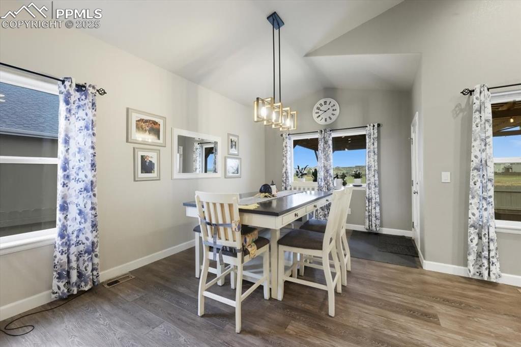 Image 11 of 47: Dining area with dark wood-type flooring, vaulted ceiling, plenty of natura