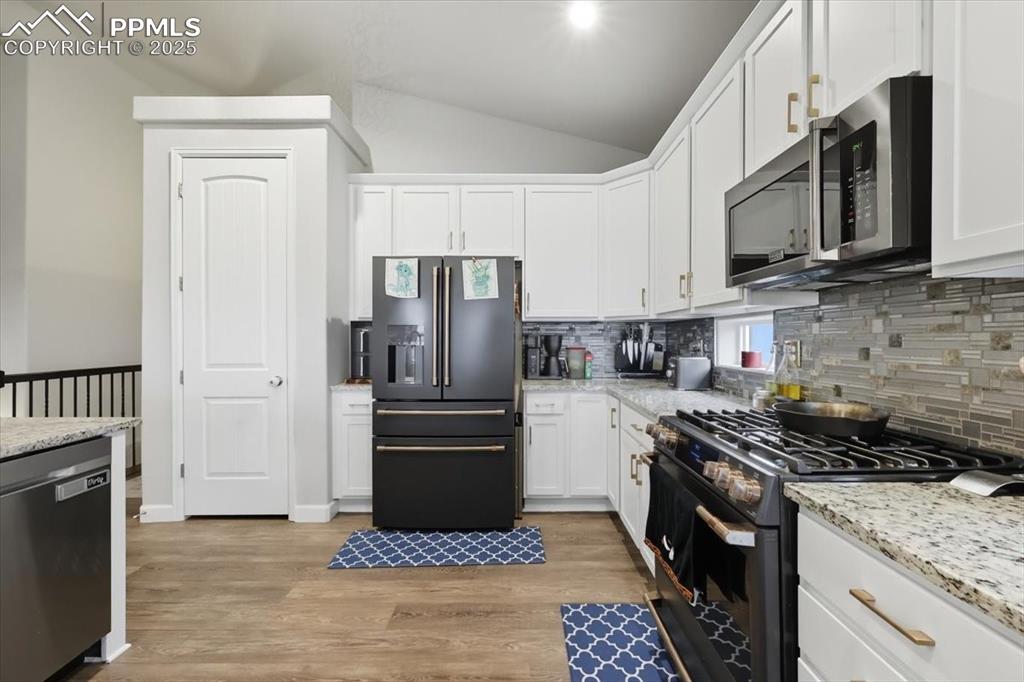 Image 13 of 47: Kitchen featuring appliances with stainless steel finishes, vaulted ceiling