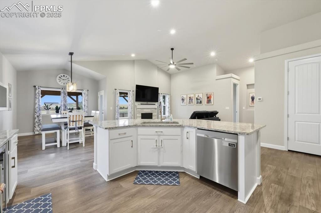 Image 15 of 47: Kitchen with white cabinetry, lofted ceiling, dishwasher, light stone count