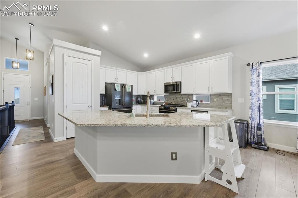 Image 17 of 47: Kitchen with a breakfast bar area, white cabinets, light stone countertops,