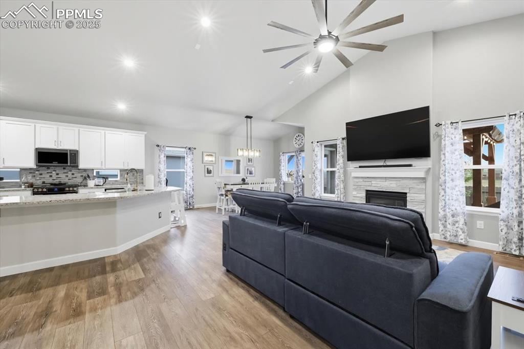 Image 18 of 47: Living room featuring light wood-style flooring, high vaulted ceiling, a st