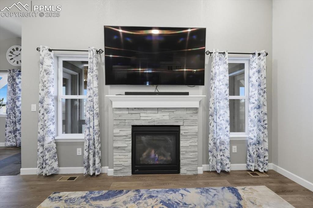Image 9 of 47: Living area featuring dark wood-style floors and a stone fireplace