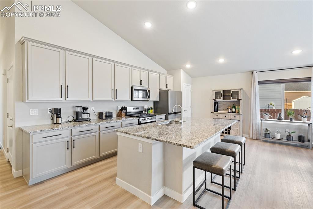 Image 19 of 46: Kitchen with light stone countertops, a kitchen island with sink, a kitchen