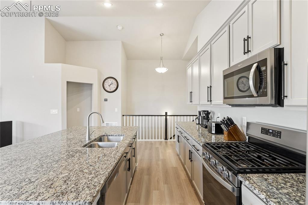 Image 21 of 46: Kitchen with appliances with stainless steel finishes, light stone counters