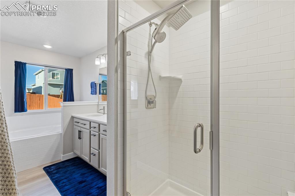 Image 28 of 46: Bathroom featuring vanity, a stall shower, light wood-type flooring, a gard
