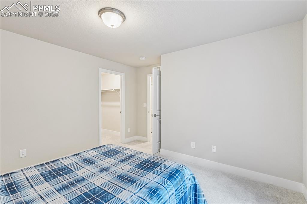 Image 37 of 46: Bedroom with a walk in closet and carpet