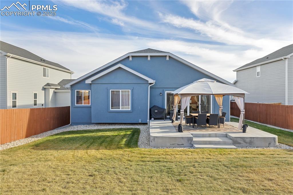 Image 46 of 46: Back of property with a fenced backyard, a gazebo, a patio, and stucco sidi