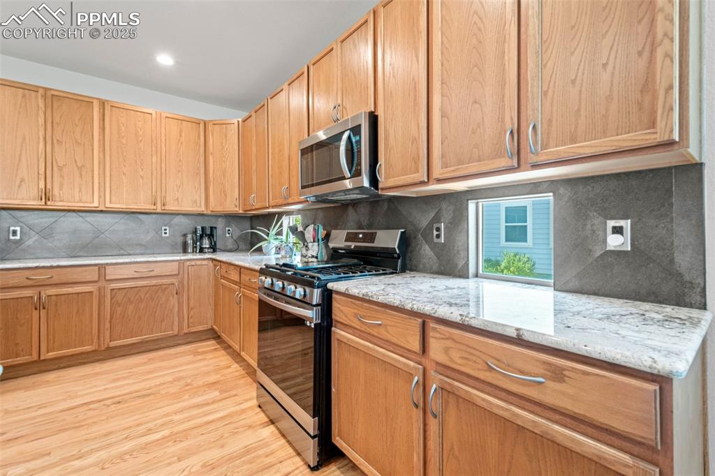 Image 10 of 39: Kitchen featuring stainless steel appliances, decorative backsplash, light 