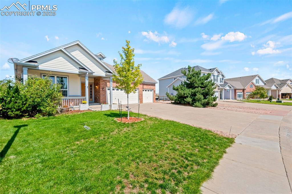 Image 2 of 39: View of front of house featuring a front yard, driveway, a porch, brick sid