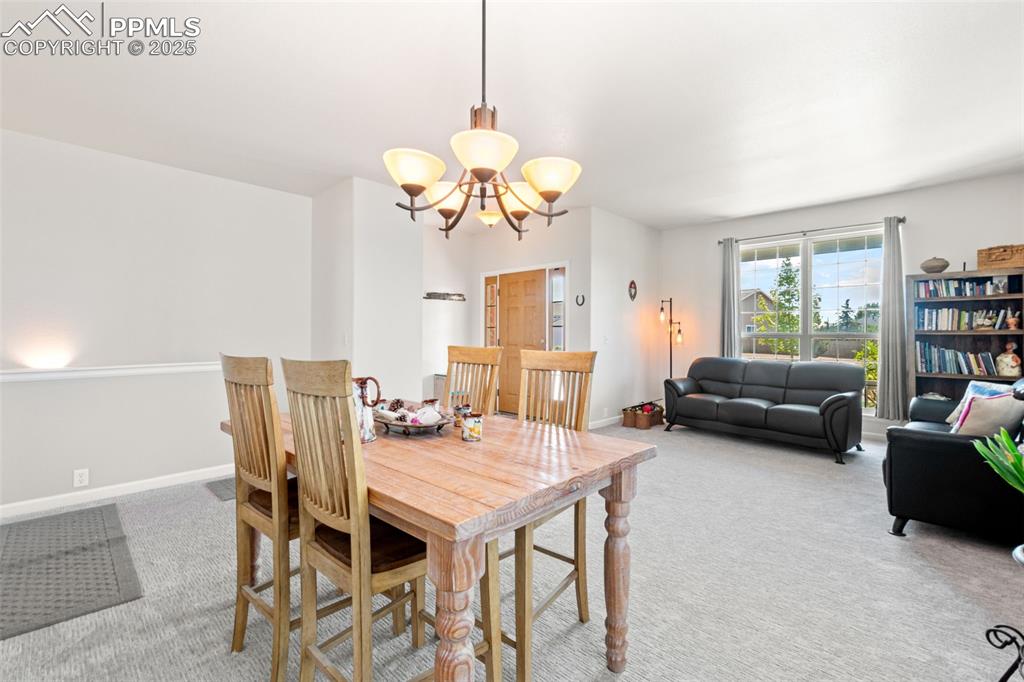 Image 6 of 39: Dining area featuring light carpet and a chandelier