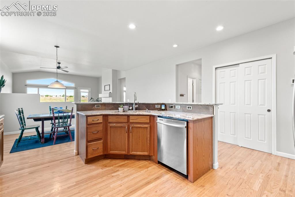Image 9 of 39: Kitchen featuring brown cabinetry, a center island with sink, stainless ste