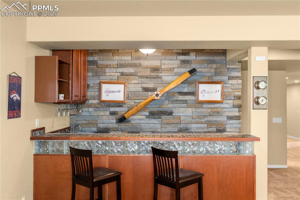 Image 27 of 43: Wet bar with stacked stone feature wall. 