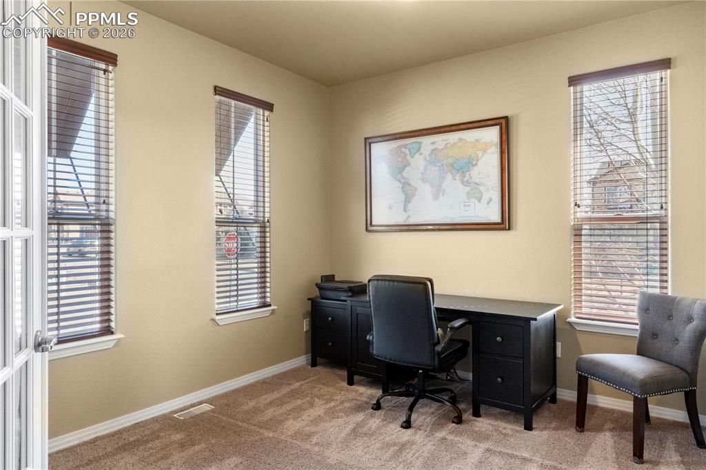 Image 4 of 43: Just off the entry is the main level office with carpet and French doors. 