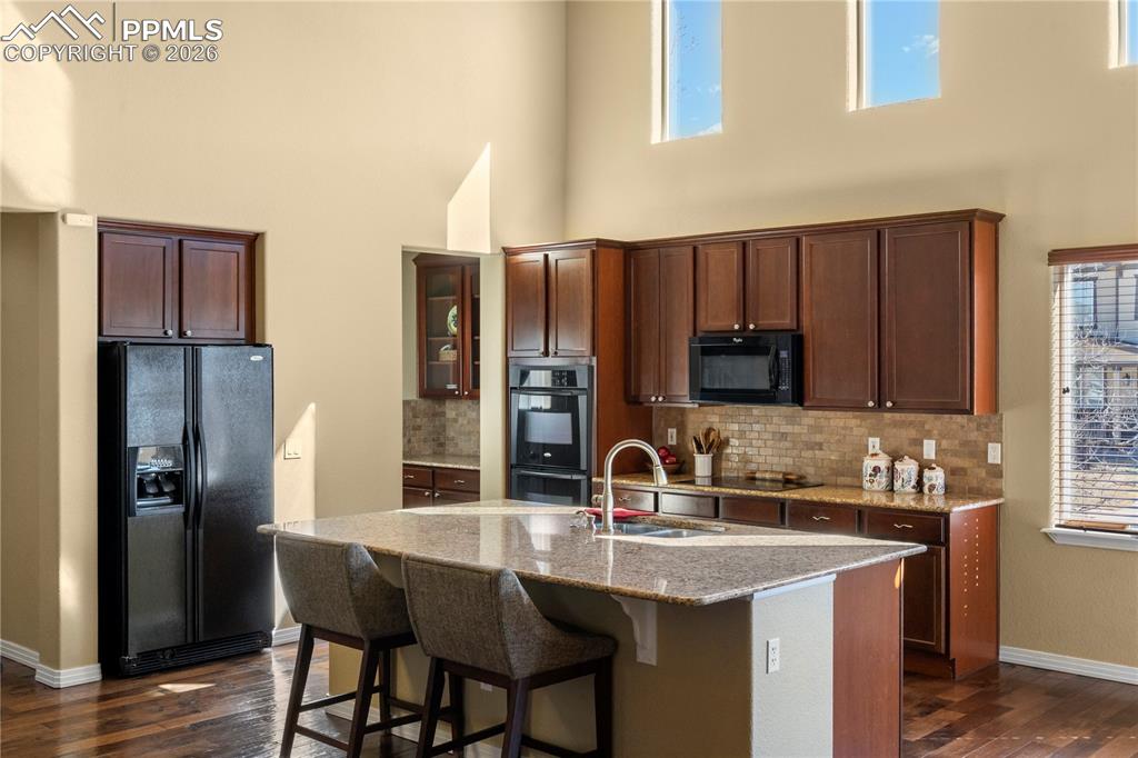 Image 6 of 43: Kitchen boasts wood flooring, soaring ceilings, large island with breakfast