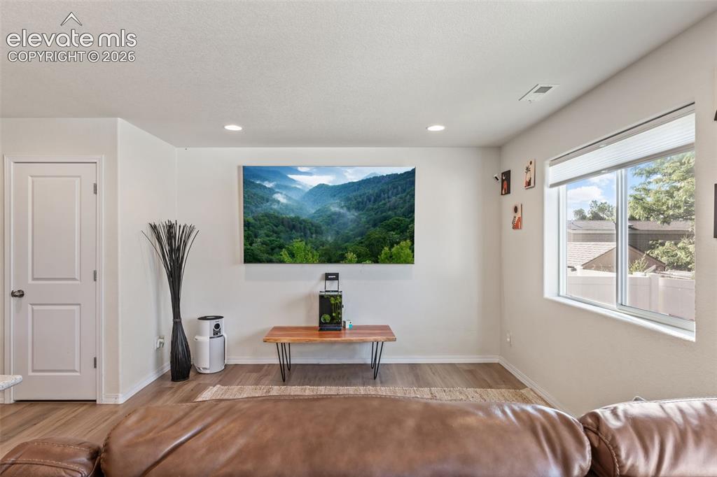 Image 10 of 38: Bright living area featuring wood-finish flooring, recessed lighting, and a