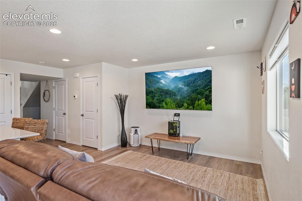 Image 11 of 38: Living area featuring wood-finish flooring, recessed lighting, and a window