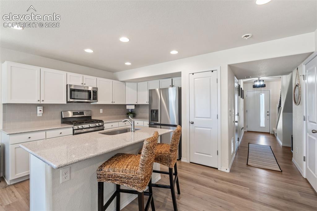 Image 12 of 38: Kitchen featuring white shaker cabinetry, stainless steel appliances, a til