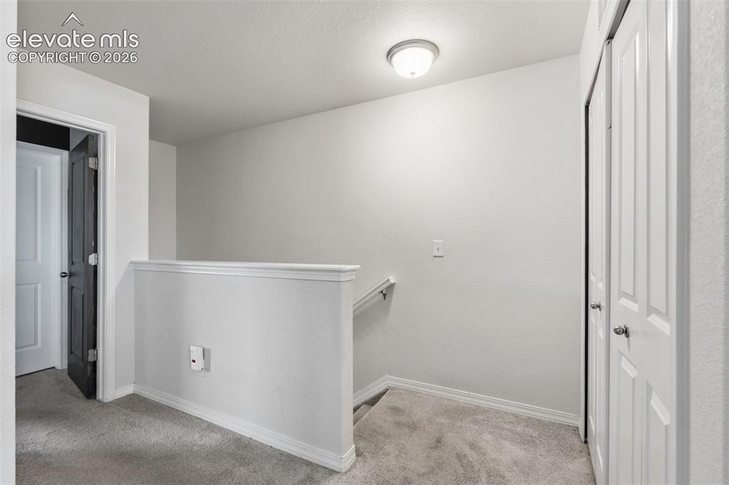 Image 17 of 38: Carpeted landing featuring white walls, white trim, a flush-mount ceiling l