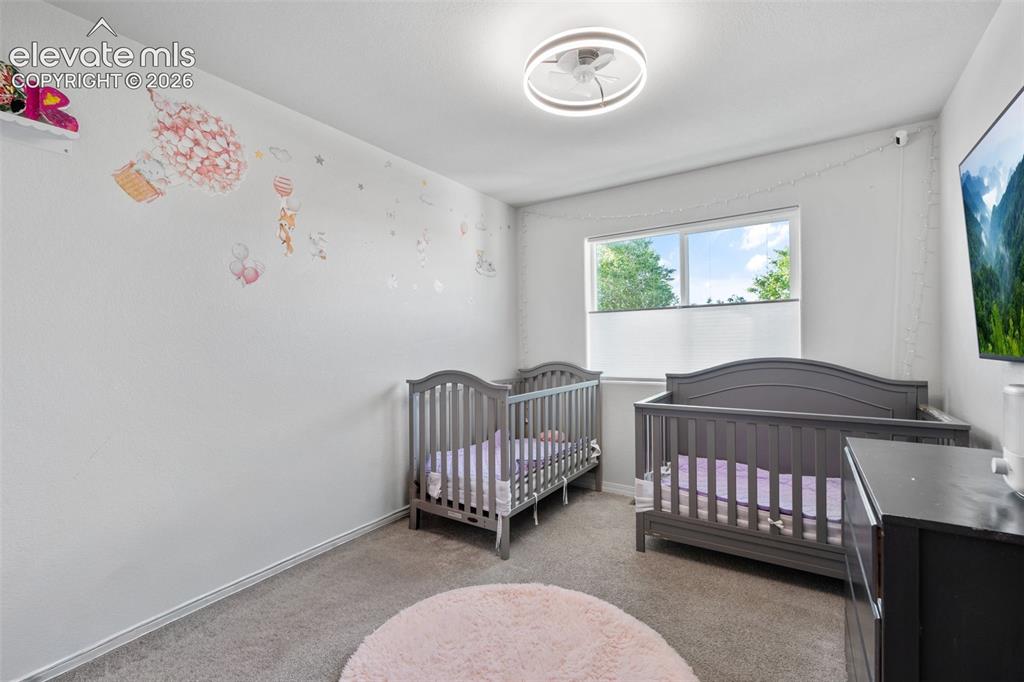 Image 26 of 38: Spacious room featuring light gray carpet flooring, white walls, and a mode