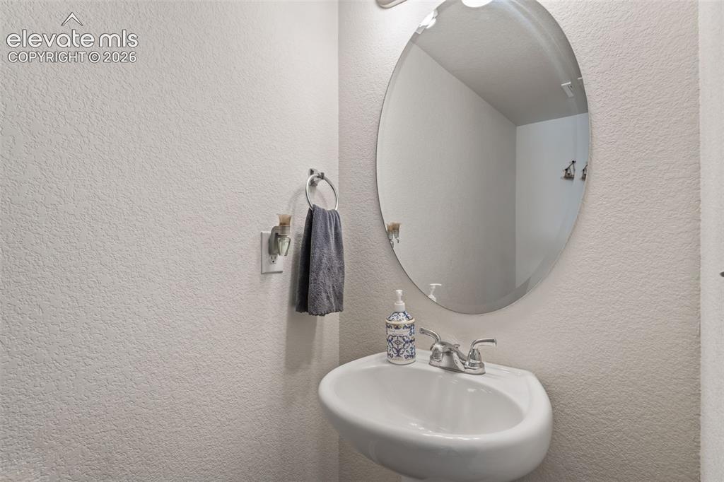 Image 28 of 38: Wall-mounted pedestal sink with chrome faucet and oval mirror
