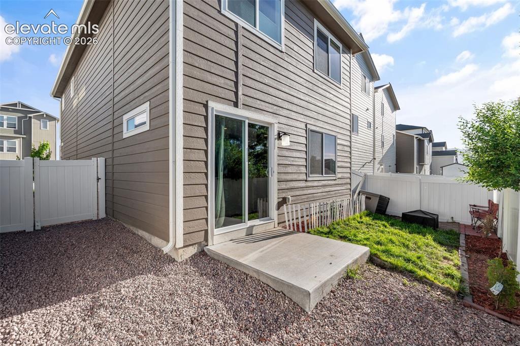 Image 31 of 38: Rear exterior featuring horizontal siding, a sliding glass door, and a conc