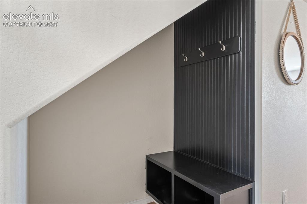 Image 8 of 38: Built-in storage niche with a black slatted accent wall and integrated coat