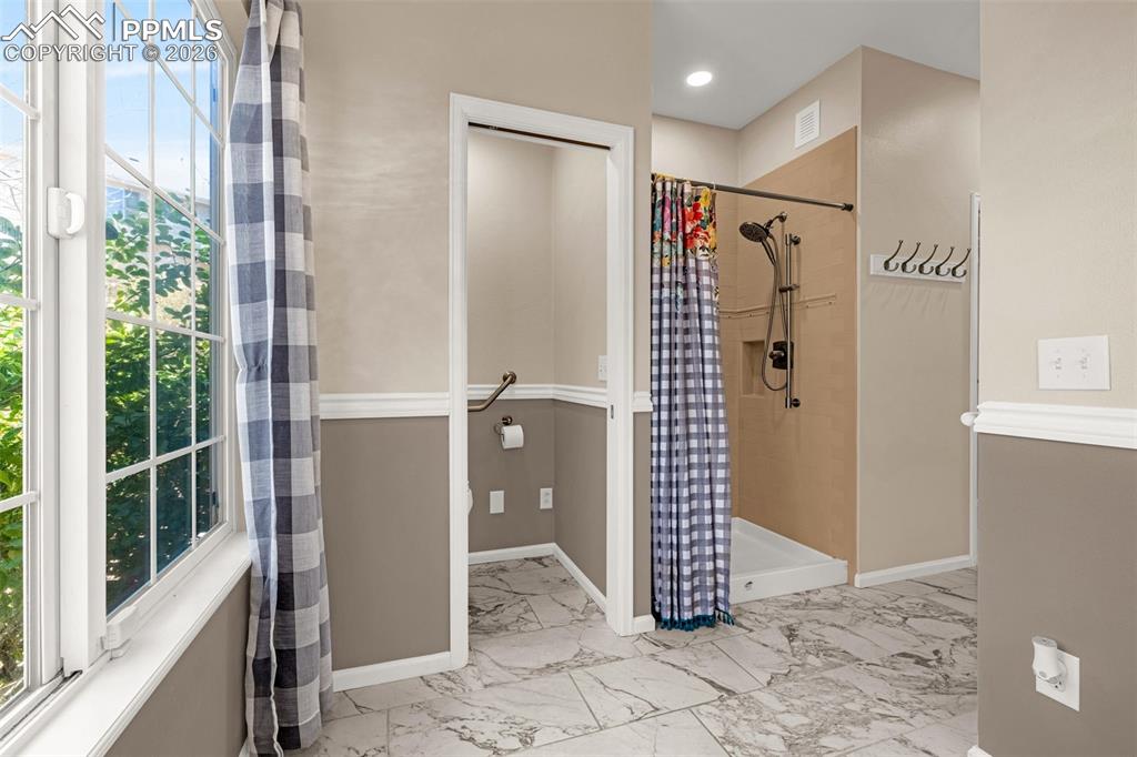 Image 17 of 39: This bathroom has been equipped with handicap rails, wide hallway and showe