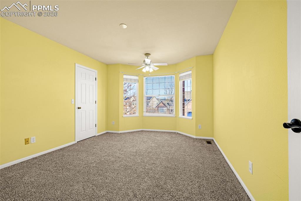 Image 20 of 39: This upper level bedroom boasts a bay window and sunshine colored walls