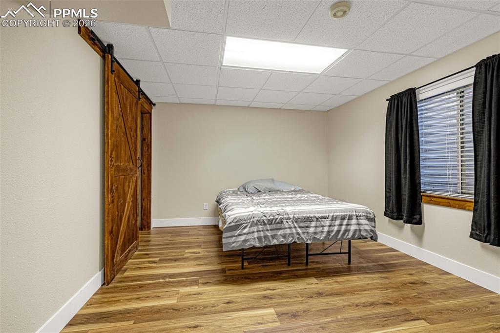 Image 26 of 39: Spacious basement level bedroom accented with barn door style walk in close