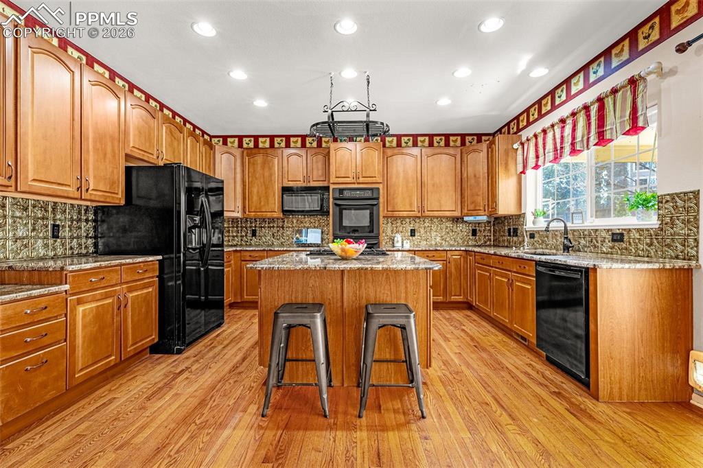 Image 6 of 39: Exceptional natural wood kitchen accented with granite countertops and blac