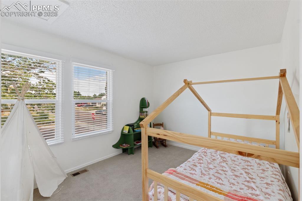 Image 14 of 24: Second bedroom upstairs with carpet and natural light.