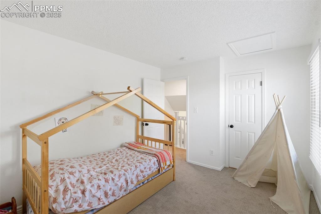 Image 15 of 24: Carpeted bedroom with attic access and a walk-in closet.