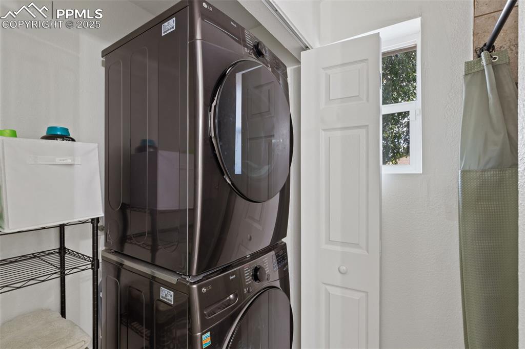 Image 17 of 24: downstairs laundry room with stacked washer / dryer and storage.