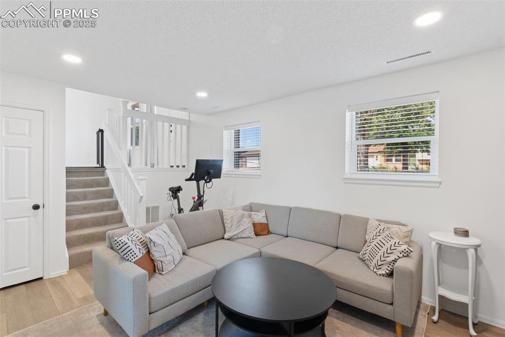 Image 7 of 24: family room with plenty of natural light, LVP flooring, stairway, and reces