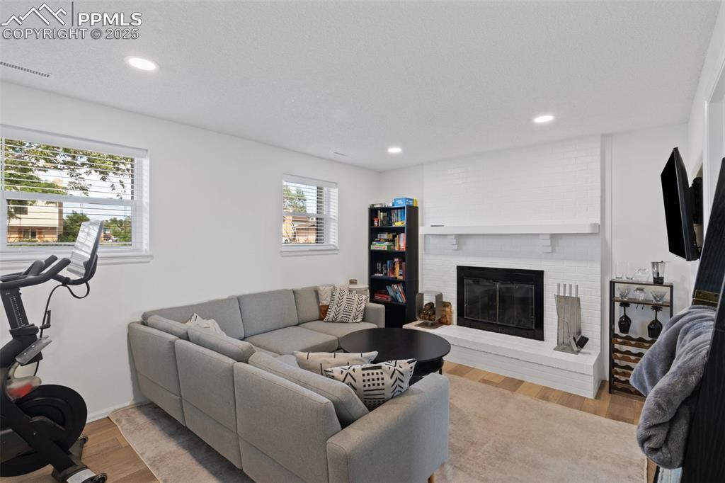 Image 8 of 24: Family room with LVP floors, a wood burning fireplace with brick surround,