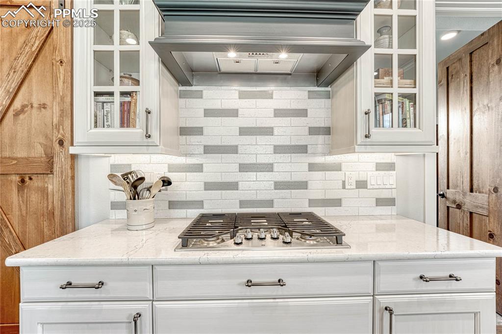 Image 17 of 50: Stone countertops, 
Backsplash, White Cabinetry,