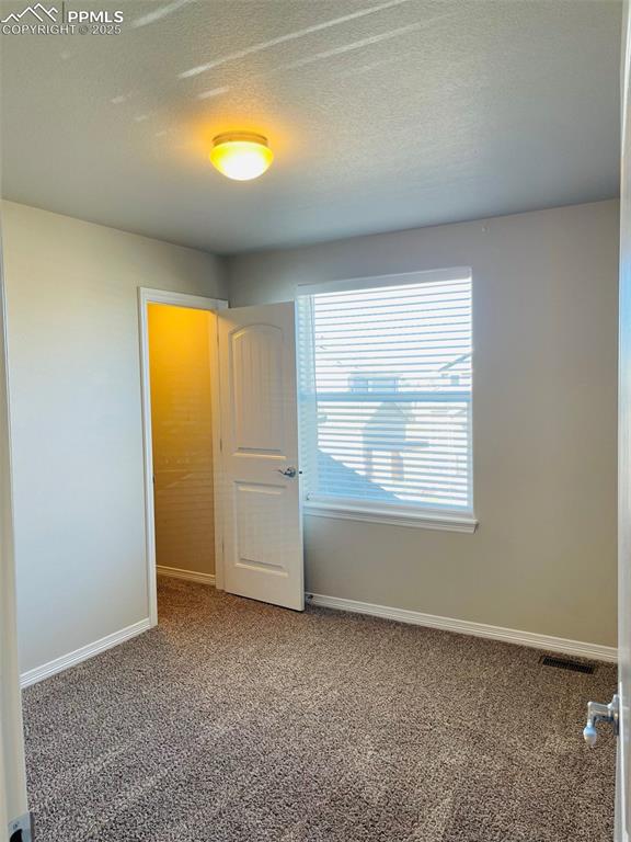 Image 16 of 19: Unfurnished bedroom with carpet and a textured ceiling