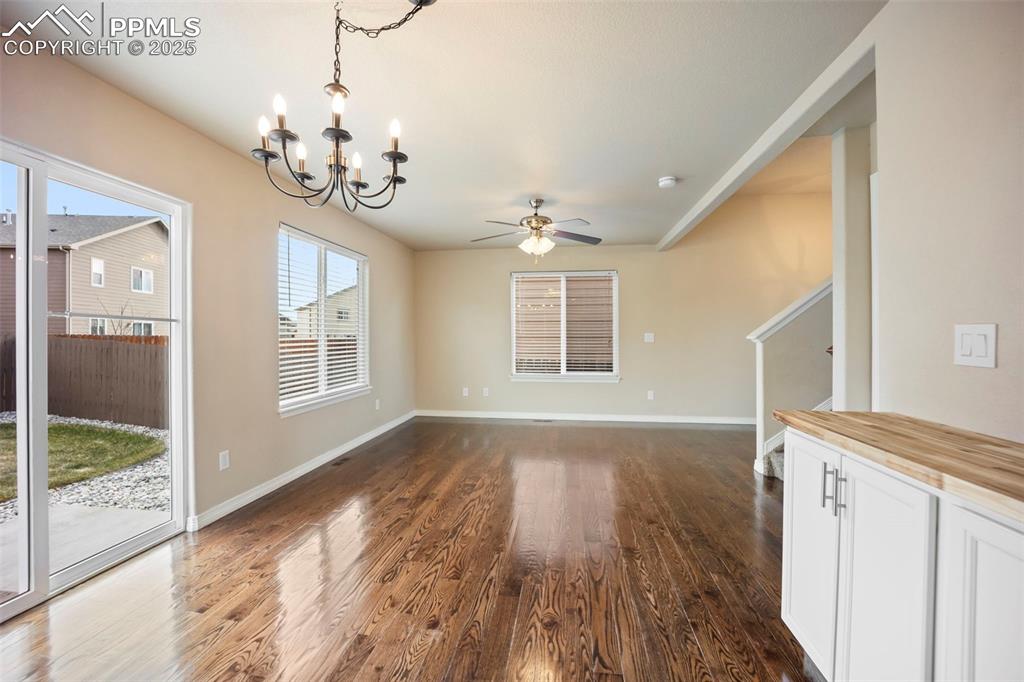 Image 12 of 39: Unfurnished living room with dark wood-style floors, a chandelier, and a ce
