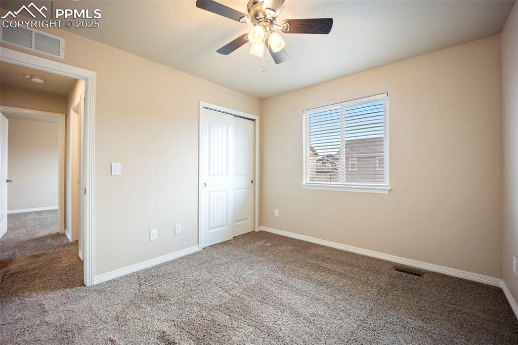 Image 17 of 39: Unfurnished bedroom with carpet, a closet, and a ceiling fan