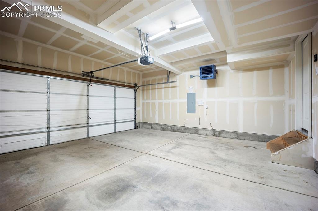Image 30 of 39: Garage with electric panel, a heating unit, and a garage door opener
