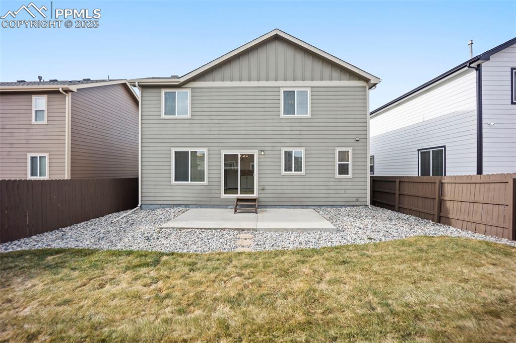 Image 33 of 39: Rear view of house with board and batten siding, a patio area, and a fenced