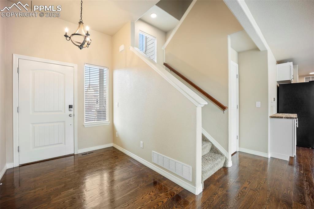 Image 4 of 39: Entrance foyer with stairway, dark wood-style floors, and a chandelier