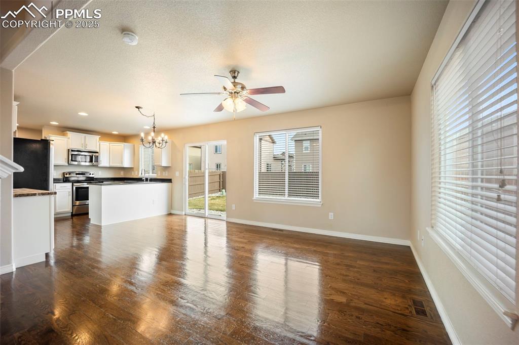 Image 6 of 39: Unfurnished living room featuring a chandelier, dark wood-type flooring, ce