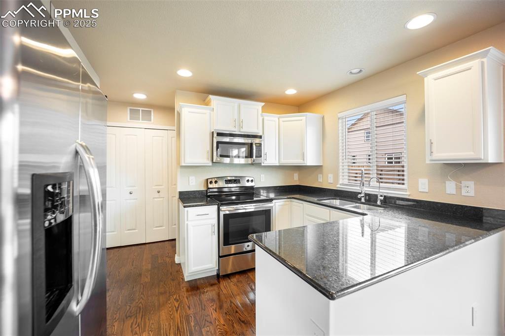 Image 7 of 39: Kitchen featuring appliances with stainless steel finishes, dark stone coun
