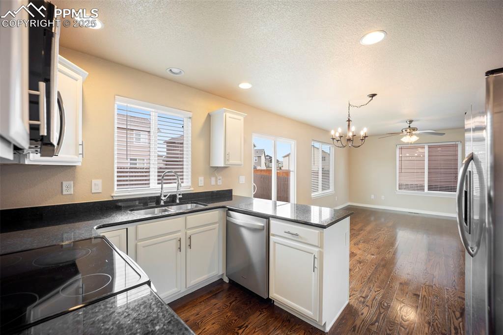 Image 9 of 39: Kitchen with a peninsula, white cabinets, appliances with stainless steel f