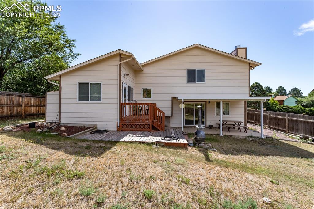 Image 37 of 46: Large backyard with deck and covered patio. 
